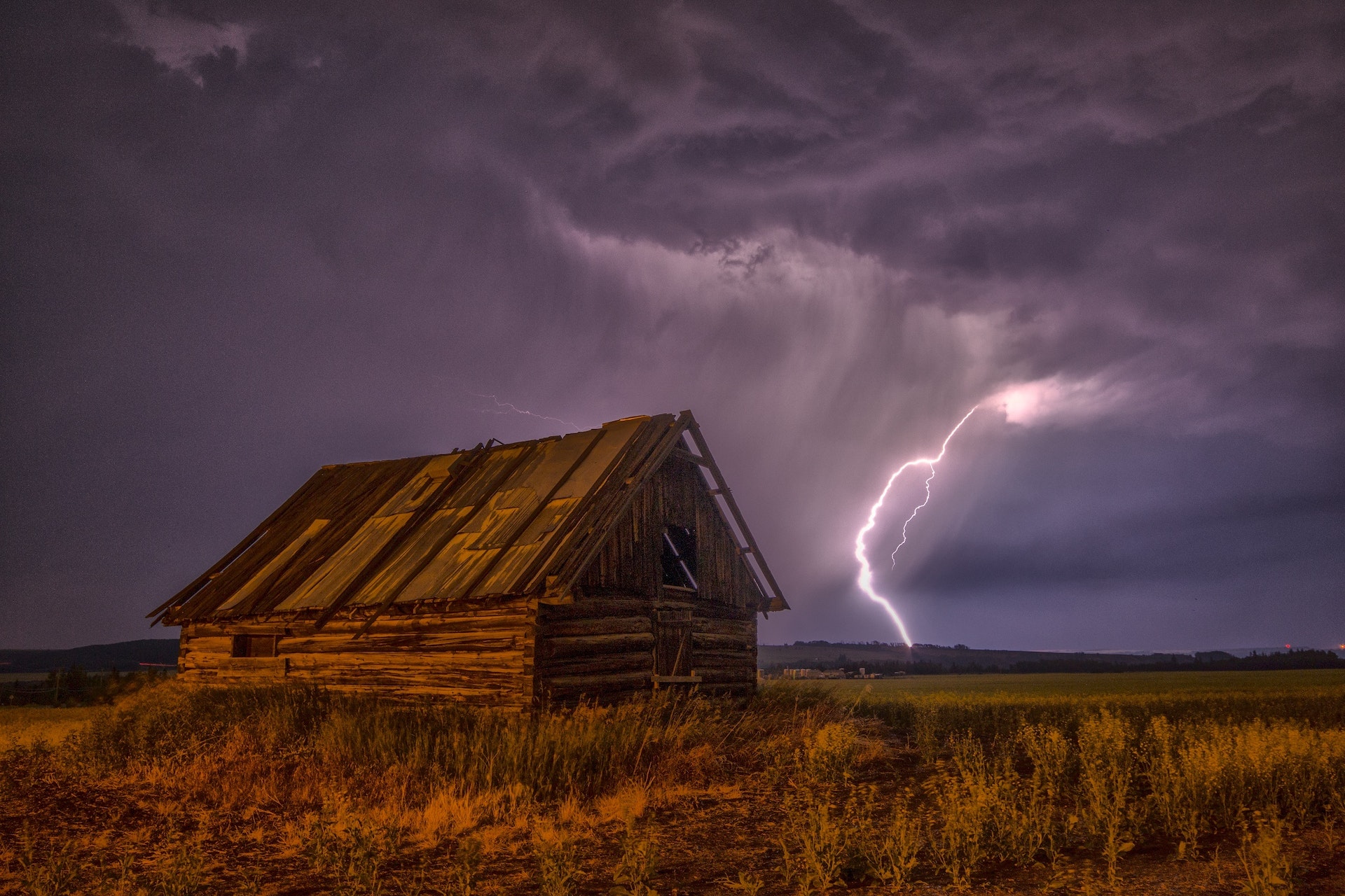 Brown and Beige Wooden Barn Surrounded with Brown Grasses under Thunderclouds